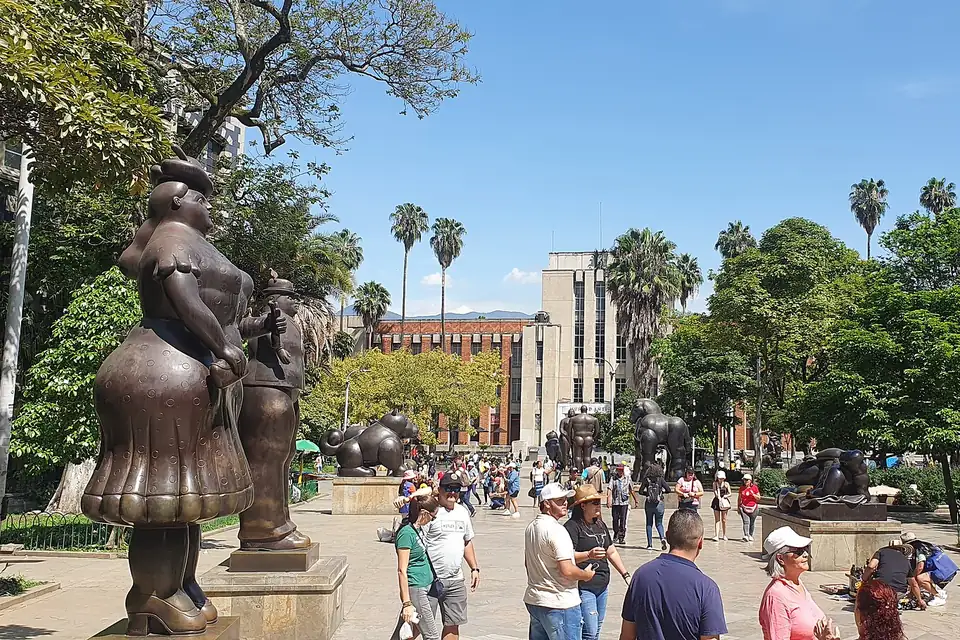 Plaza Botero de Medellín con esculturas de bronce y gente caminando bajo el sol